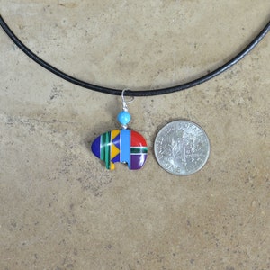 May include: A colorful Native American-style buffalo pendant necklace with a turquoise bead on a black leather cord. The pendant is about the size of a US quarter.