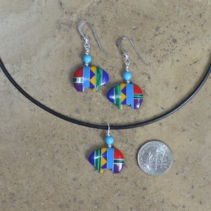 May include: A set of turquoise and multi-colored Native American-style earrings and a necklace with a pendant. The pendant and earrings are shaped like a stylized teepee.