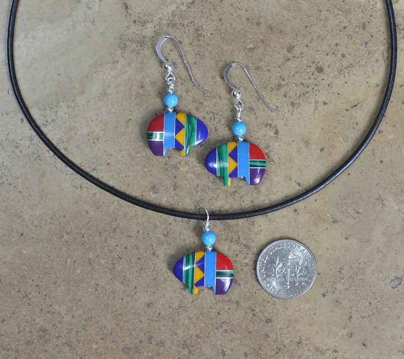 May include: A set of turquoise and multi-colored Native American-style earrings and a necklace with a pendant. The pendant and earrings are shaped like a stylized teepee.