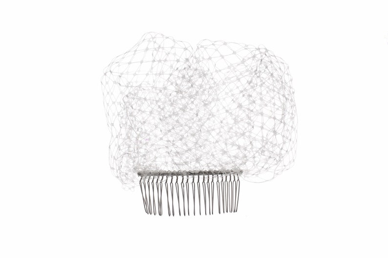 May include: White bridal veil with a comb attachment. The veil is made of a fine mesh material.
