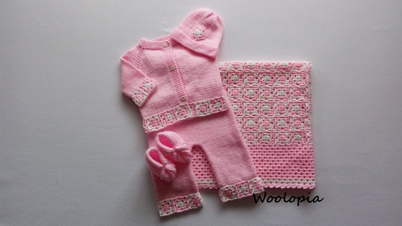 Puede incluir: Un conjunto de ropa de beb&eacute; de punto rosa con gorro, botines y manta a juego. El conjunto presenta ribetes de ganchillo blanco y un cierre de bot&oacute;n en el c&aacute;rdigan.