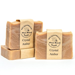 Pode incluir: Três barras de sabonete à base de plantas com um rótulo castanho que diz "White Squirrel Elements Plant Based Soap Crystal Amber".