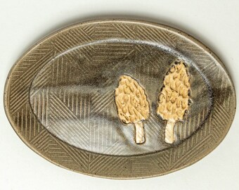 May include: A ceramic oval serving dish with a brown glaze and a geometric pattern. Two yellow-brown mushrooms are embossed on the dish.