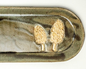 May include: A green ceramic serving dish with a textured surface and two raised, white mushroom designs.