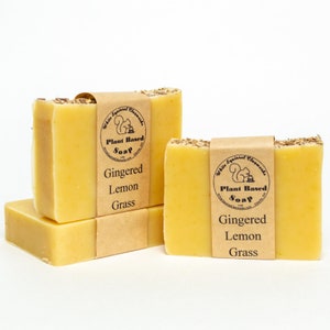 May include: Four bars of plant-based soap with a brown label that reads "White Squirrel Elements Plant Based Soap Gingered Lemon Grass".