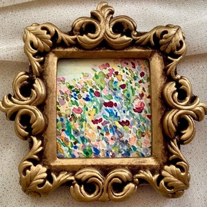 May include: A small painting of a field of colorful flowers in a gold ornate frame.