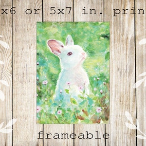 May include: A watercolor print of a white rabbit in a field of green grass and small pink flowers. The print is available in 4x6 or 5x7 inch sizes and is labeled "frameable". The rabbit is looking upwards with its ears perked.