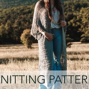 May include: A long, gray knitted cardigan with fringe detailing. The cardigan is worn over a white top and blue jeans.