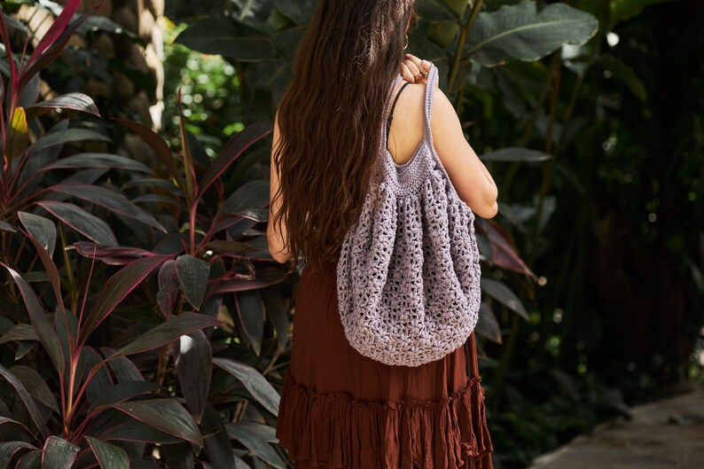 May include: A woman wearing a brown dress with a crocheted purple tote bag.