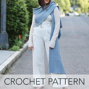 Puede incluir: Una bufanda de ganchillo azul claro drapeada sobre un suéter blanco y pantalones blancos. La bufanda es larga y rectangular, con una textura acanalada. El texto "CROCHET PATTERN" está en la parte inferior de la imagen.