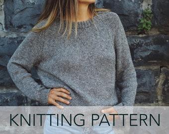 Può includere: Un maglione di lana grigio con scollo rotondo. Il maglione è indossato da una persona in piedi davanti a un muro di pietra. Il testo "KNITTING PATTERN" è nella parte inferiore dell'immagine.