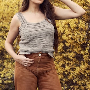 Peut inclure: Une femme portant un d&eacute;bardeur en crochet marron clair avec un pantalon taille haute marron.