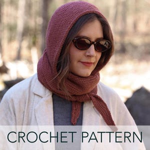 Puede incluir: Un patrón de crochet para una bufanda con capucha de color rosa oscuro. La bufanda la lleva puesta una persona con el pelo castaño y gafas de sol. La imagen tiene el texto "CROCHET PATTERN" en la parte inferior.