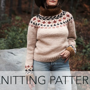 May include: A beige knitted sweater with a brown turtleneck and a colorful Fair Isle pattern around the neck and cuffs. The sweater is worn by a person standing in a forest setting.