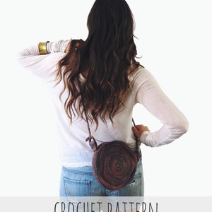 May include: A brown and purple crocheted round bag with a long strap worn over the shoulder. The bag is worn by a person wearing a white long-sleeved shirt and denim shorts. CROCHET PATTERN is written in black text on a white background.