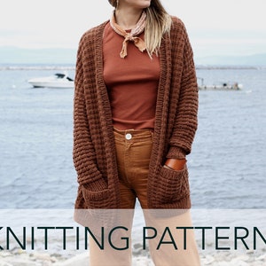 May include: A brown knitted cardigan with pockets and a waffle stitch pattern. The cardigan is open at the front and has long sleeves. The model is wearing the cardigan over a rust-coloured t-shirt and brown trousers.