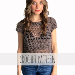 May include: A brown crochet top with a loose, open-weave pattern. The top has short sleeves and a round neckline. The model is wearing the top with blue jeans.