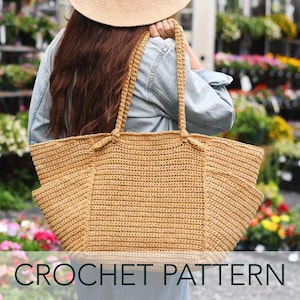 Puede incluir: Un bolso tote grande de crochet beige con dos bolsillos laterales y asas resistentes. El bolso se lleva al hombro. El texto "CROCHET PATTERN" se muestra en la parte inferior de la imagen.