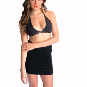 Puede incluir: Una mujer con un top halter de crochet negro y una minifalda negra.