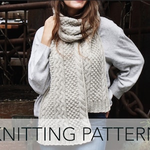 May include: A white knitted scarf with a cable knit pattern. The scarf is being worn by a person. The text "KNITTING PATTERN" is at the bottom of the image.