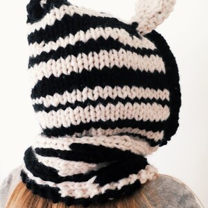 Puede incluir: Un gorro de punto de rayas blancas y negras con orejeras. El gorro est&aacute; hecho de un hilo suave y grueso y tiene una sensaci&oacute;n acogedora y c&aacute;lida.