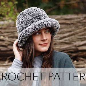 May include: A crochet pattern for a gray and white fuzzy bucket hat. The hat is worn by a person with long brown hair. The text "CROCHET PATTERN" is displayed at the bottom of the image.