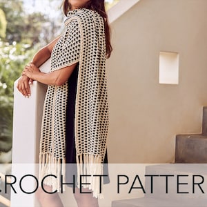 May include: A crocheted scarf with a black and white geometric pattern and fringe. The scarf is draped over a person's shoulders.