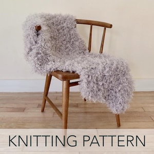 May include: A soft, fluffy, light gray knitted throw blanket draped over a wooden chair.  The blanket is made with a fuzzy yarn and has a loose, open weave.  KNITTING PATTERN.