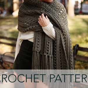 May include: A crocheted shawl in a dark green color with a lacy pattern and fringe. The shawl is draped over a person's shoulders. CROCHET PATTERN is written in black text on a white background.