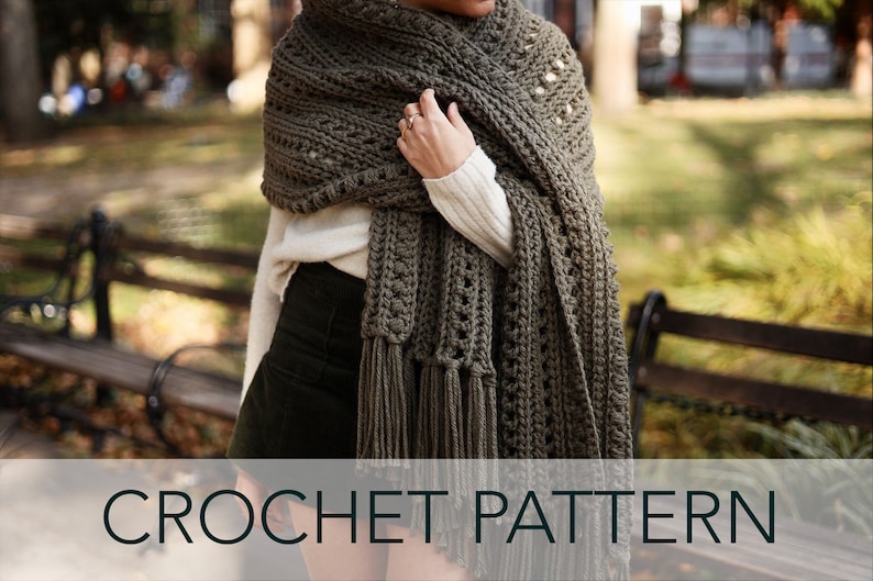 May include: A crocheted shawl in a dark green color with a lacy pattern and fringe. The shawl is draped over a person's shoulders. CROCHET PATTERN is written in black text on a white background.