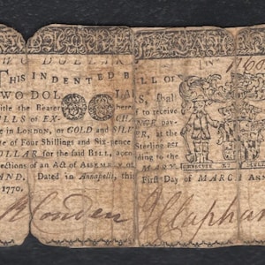 Puede incluir: Antiguo billete de dos dólares de 1770, con grabados y texto intrincados. El billete está envejecido con desgaste visible, mostrando su importancia histórica. El texto incluye "TWO DOLLARS" y firmas.