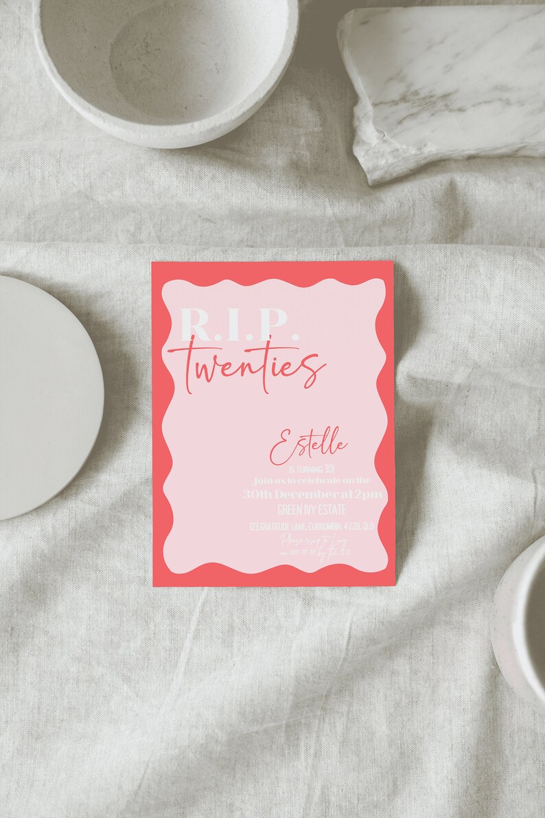 May include: A pink and coral invitation card with the text "R.I.P. Twenties" and event details. The card has a wavy coral border and is set on a neutral linen surface, with decorative bowls in the background.