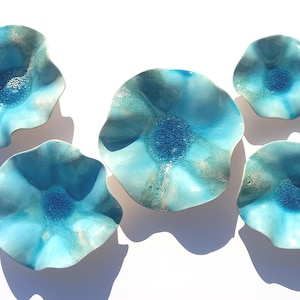 May include: A collection of five ceramic bowls with wavy, scalloped edges. Each bowl features a gradient glaze transitioning from a deep, textured cobalt blue center to a lighter turquoise and white rim, creating a fluid, organic appearance.