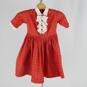 May include: A red dress with a white collar and a white ruffle trim. The dress has a small floral pattern.