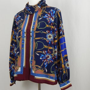 May include: A long-sleeved button-up shirt with a blue background and a colorful pattern of floral designs and gold chains. The shirt has a maroon collar and cuffs.