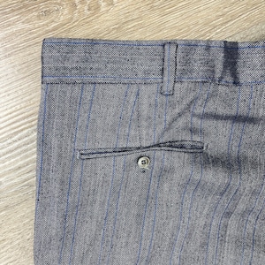 May include: A pair of gray pants with thin blue stripes and a herringbone pattern. The pants have a button closure and a single back pocket.
