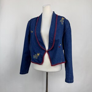 May include: A blue denim jacket with red stitching and embroidered colourful animal designs.