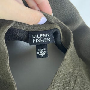 Peut inclure: Une &eacute;tiquette de v&ecirc;tement noire et blanche avec le texte "Eileen Fisher" et "Made in USA of Italian Fabric S".