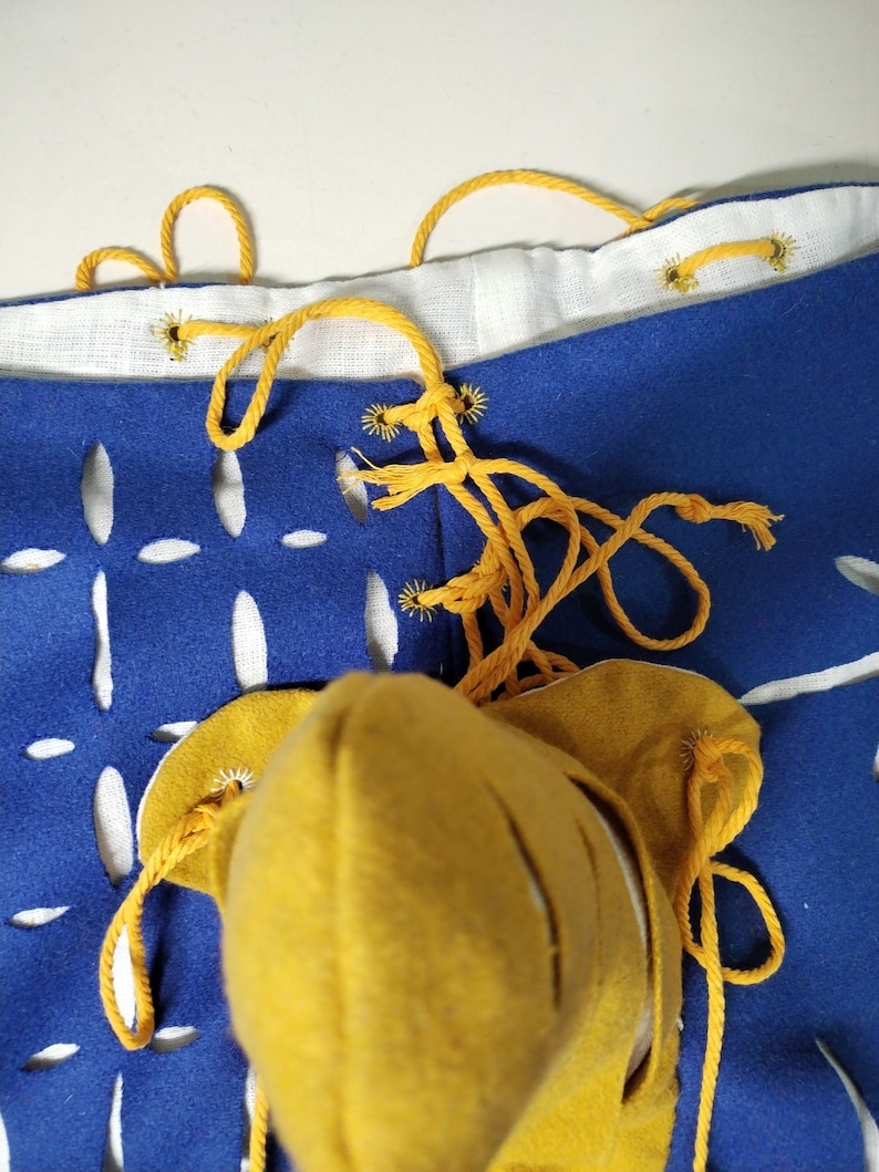 May include: A pair of blue pants with white cutouts and yellow laces. The pants are tied at the waist with a yellow cord.