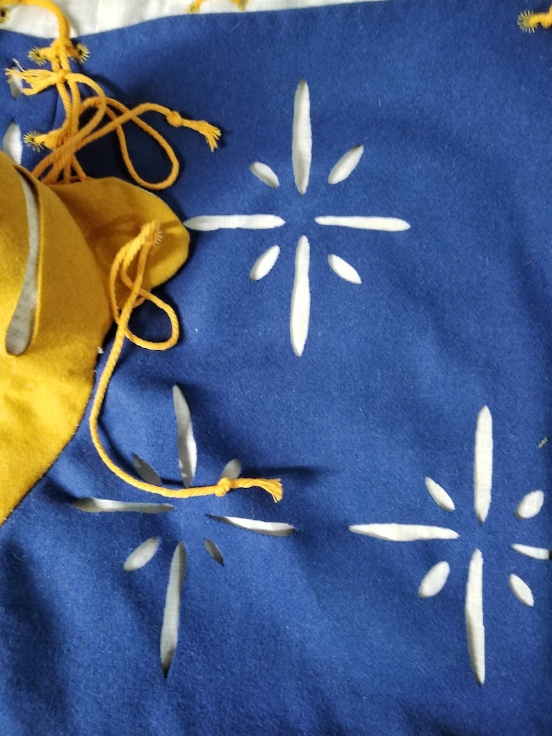 May include: A blue fabric banner with three white star-shaped cutouts. The banner has a yellow fabric border and yellow string ties.