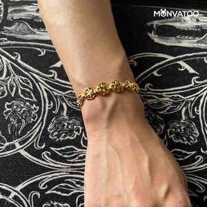 The Golden Constellar Bracelet is worn on a woman's wrist.