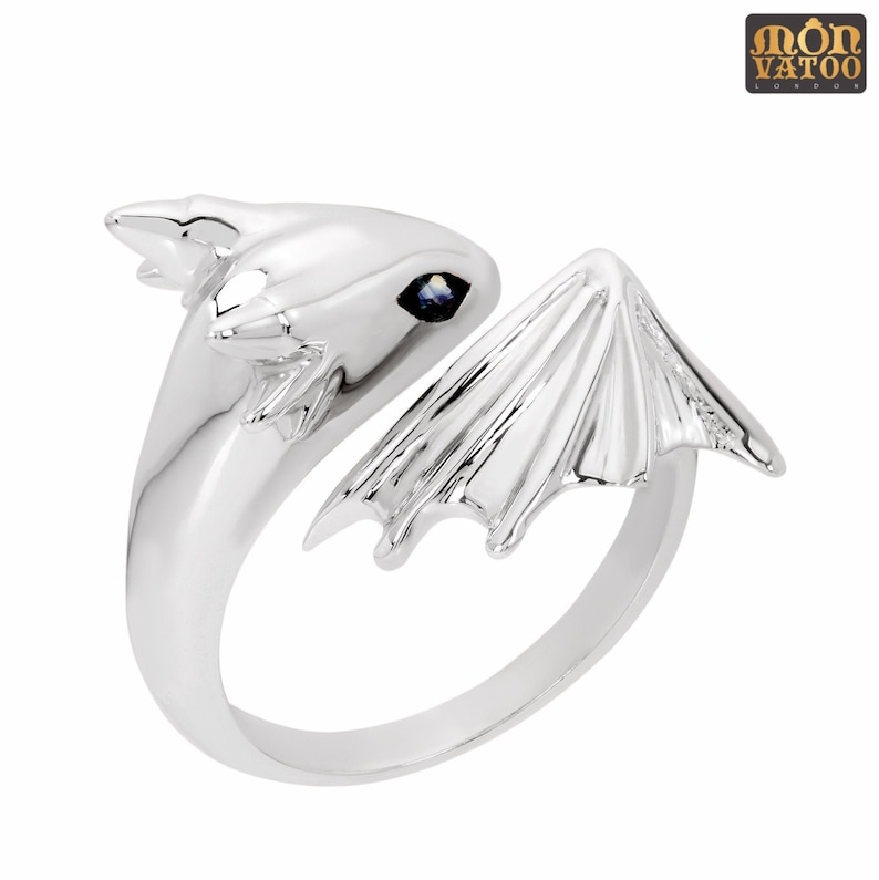 May include: A silver ring shaped like a dragon with a blue gemstone in its eye.