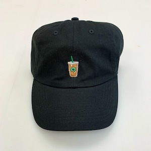 May include: Black baseball cap with an embroidered coffee drink design. The design features a brown coffee cup with a green straw and a green logo. The cap is made of a soft fabric and has a curved brim.