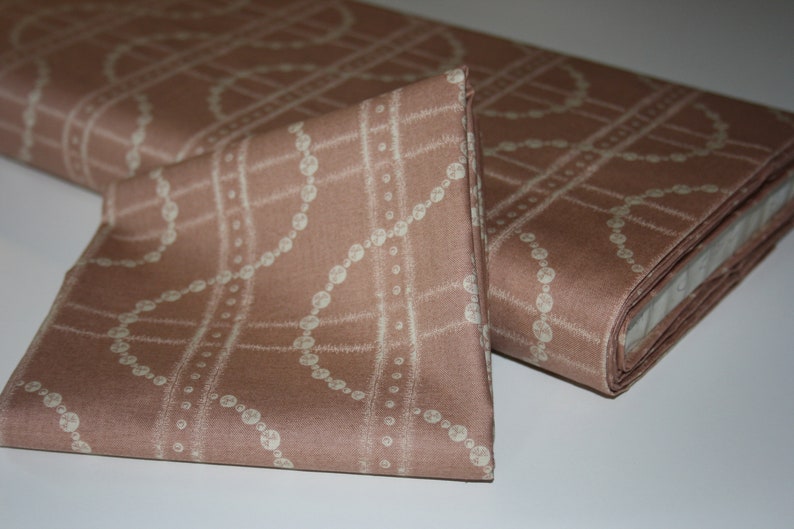 May include: A close-up of a brown fabric with a white pearl-like pattern. The fabric is folded in half and the edges are visible.