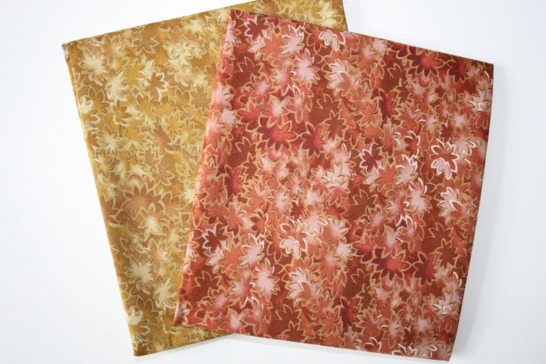 Pu&ograve; includere: Tre quadrati di tessuto con un motivo floreale. Il tessuto &egrave; di colore marrone chiaro con un motivo floreale marrone scuro sul quadrato superiore, marrone scuro con un motivo floreale marrone chiaro sul quadrato centrale e rosso con un motivo floreale marrone chiaro sul quadrato inferiore.