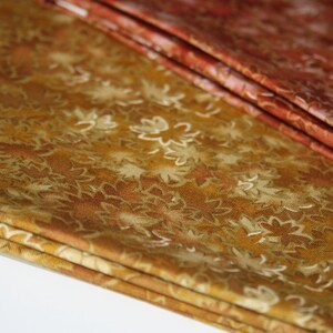 Pu&ograve; includere: Un mucchio di tessuto con un motivo floreale marrone e oro. Il tessuto &egrave; piegato in tre parti e ha una consistenza morbida e testurizzata.