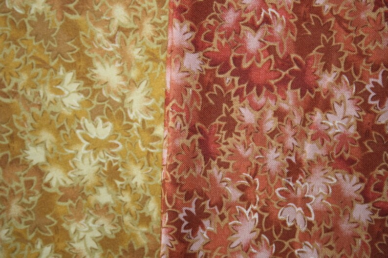 Pu&ograve; includere: Due campioni di tessuto con un motivo floreale. Il campione a sinistra &egrave; di colore marrone chiaro con un motivo floreale bianco. Il campione a destra &egrave; di colore rosso scuro con un motivo floreale bianco.