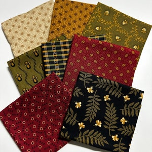 Könnte beinhalten: Ein Set aus acht Stoffquadraten mit verschiedenen Mustern in Grün-, Braun-, Rot- und Cremetönen. Die Muster umfassen kleine Blumenmuster, Punkte, Karos und Paisley.