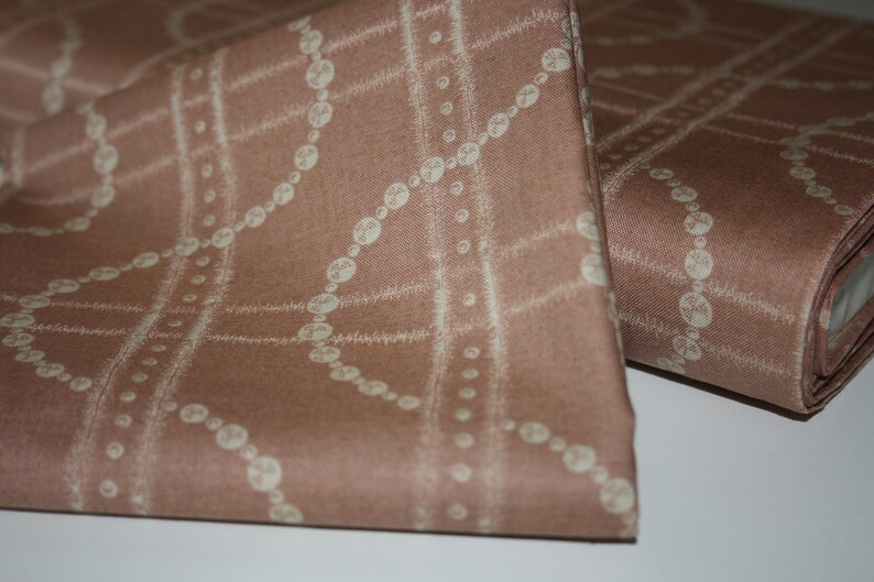 May include: A close-up of a brown fabric with a white pattern of a chain of beads. The fabric has a subtle texture.