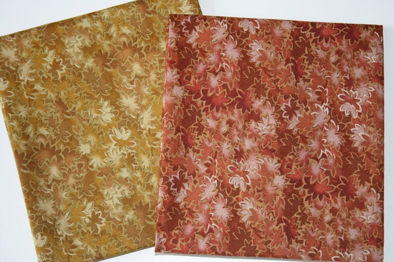 Pu&ograve; includere: Due campioni di tessuto con un motivo floreale. Un campione &egrave; di colore marrone chiaro con un motivo floreale bianco. L'altro campione &egrave; di colore rosso scuro con un motivo floreale bianco.